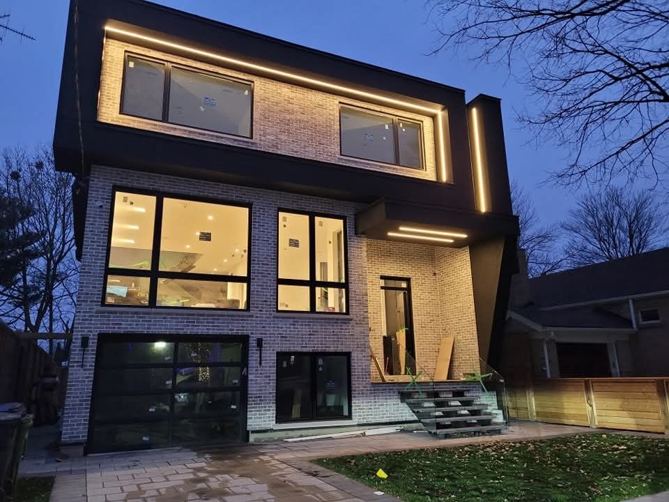 Exterior soffit pot lighting illuminating a stone-front home at dusk in Toronto
